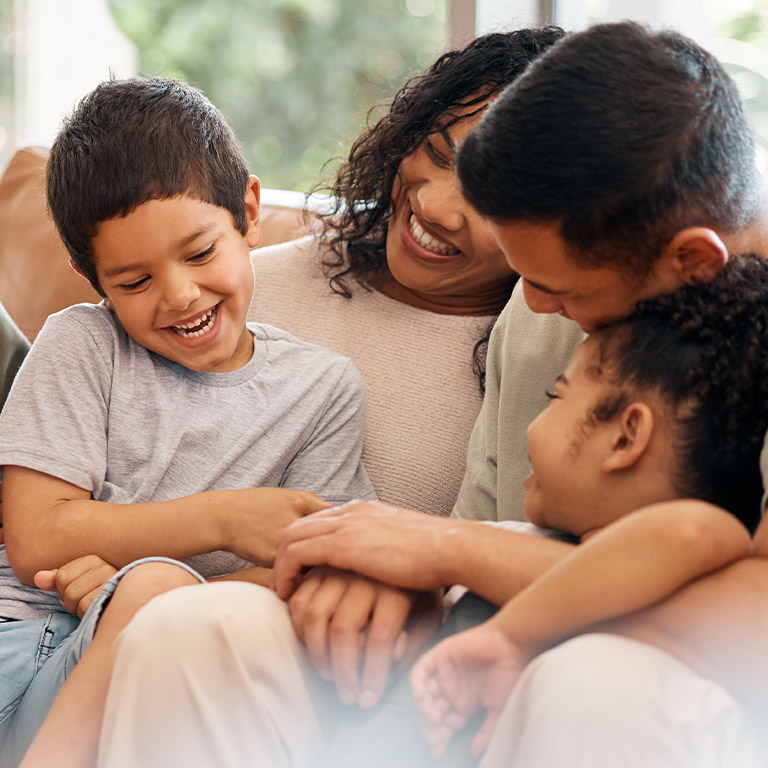 A family hugging and laughing on a couch